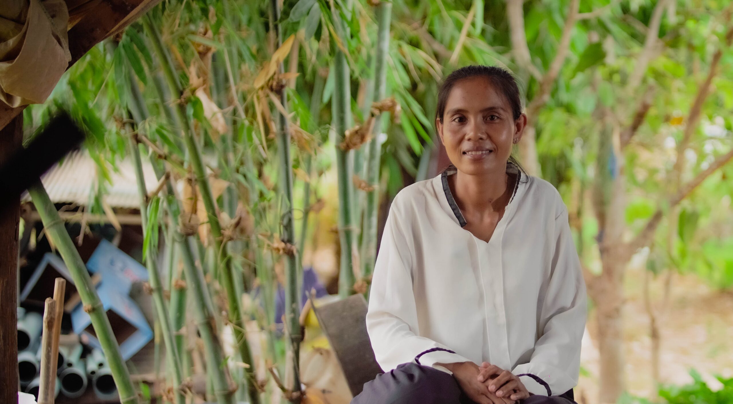 Vannet, a Cambodian woman, sits in front of a tree.